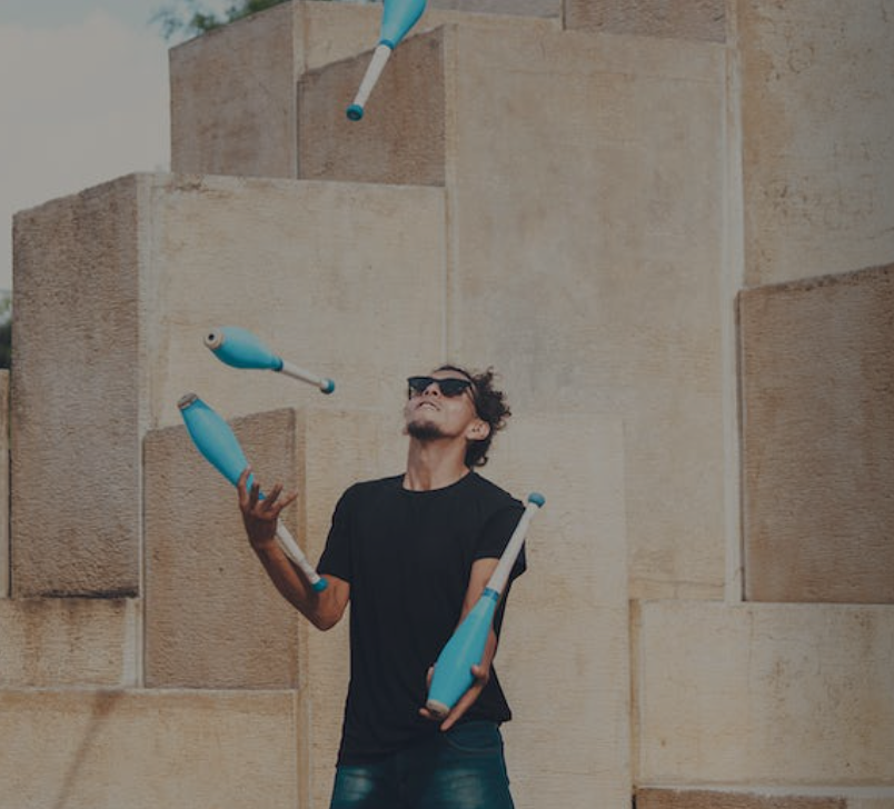 Ein junger Mann jongliert hellblaue Flaschen.